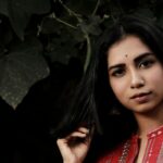 Portrait of a woman in traditional attire surrounded by lush greenery, exuding elegance and poise.